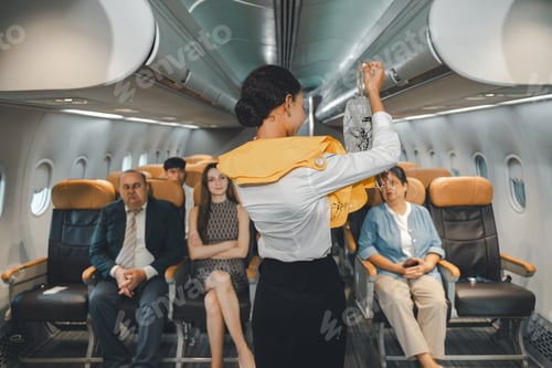 Preview: Flight attendant demonstrating oxygen mask in airplane with passengers watching in cabin