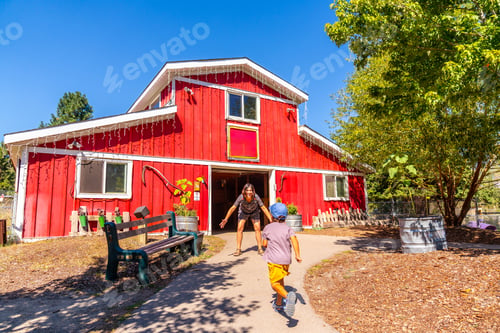 Preview: Child running towards mother in front of red barn at the bc wildlife park in kamloops