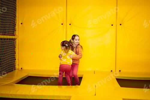 Preview: Siblings jumping on trampoline at yellow playground park.