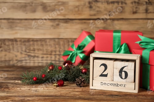 Preview: Block calendar with Boxing Day date near gifts on wooden table. Space for text