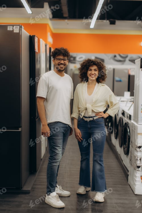 Preview: Smiling Couple Standing in Electronics Store Aisle Near Appliances