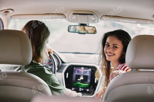 Preview: Smiling woman enjoying a car ride with a friend, interior view showcasing the dashboard and road