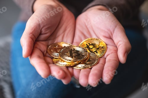 Preview: Closeup image of a woman holding and showing golden color bitcoins in hands