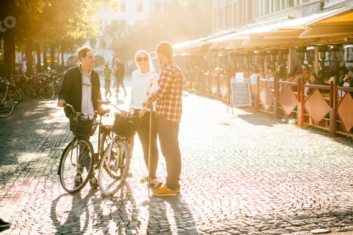 Preview: Full length of friends with bicycles and skateboard conversing on street