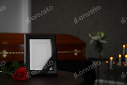 Preview: Black photo frame and red rose on table in funeral home