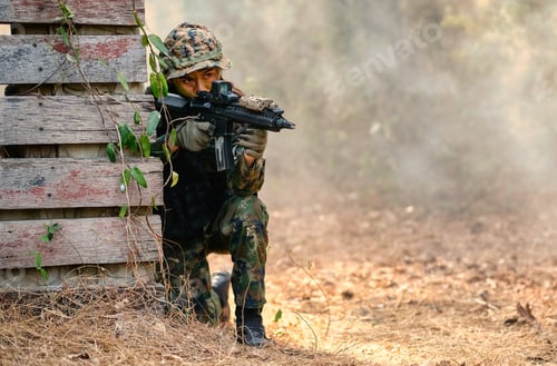 Preview: Portrait of beautiful soldier woman with combat suit sit and hold gun for shooting the enemy.