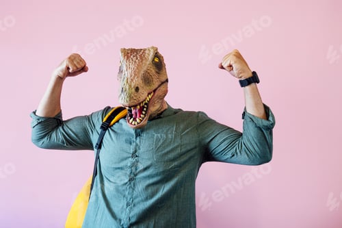 Preview: Man with lizard mask on pink background showing his muscles.