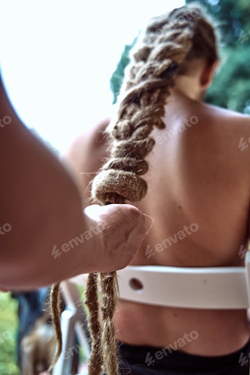 Preview: Close-up of a girl's hands, braiding a boy's dreadlocks in the garden.