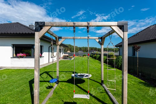 Preview: Beautiful garden with green grass, visible terrace table and house in beautiful summer weather.