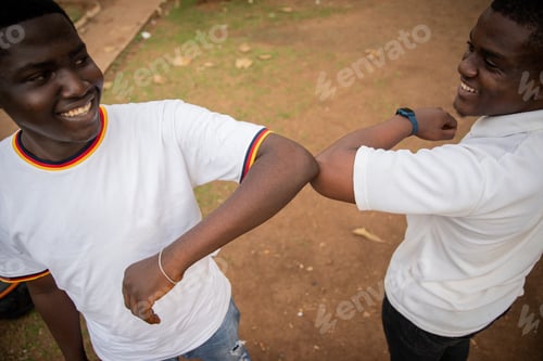Preview: Two friends in africa greeting each other with elbows to reduce contact during coronavirus pandemic