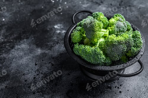 Preview: Organic Raw green broccoli cabbage in a colander. Black background. Top view. Copy space