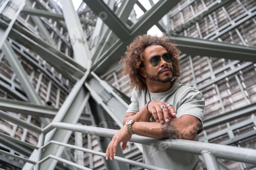 Preview: Portrait of a young man with afro hair wearing sunglasses on the stairs in the city, urban fashion