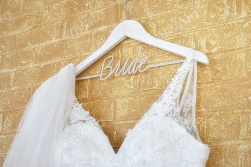 Preview: Wedding dress gown and bridal veil hanging on a Bride wooden hanger before the marriage ceremony.