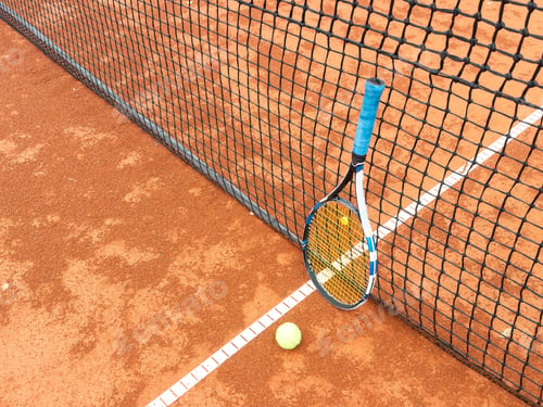 Preview: Balls and racket are lying on clay brown professional tennis court Close up of tennis balls and