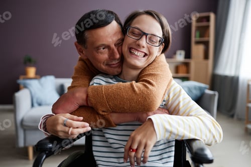 Preview: Caring father embracing happy girl with disability at home