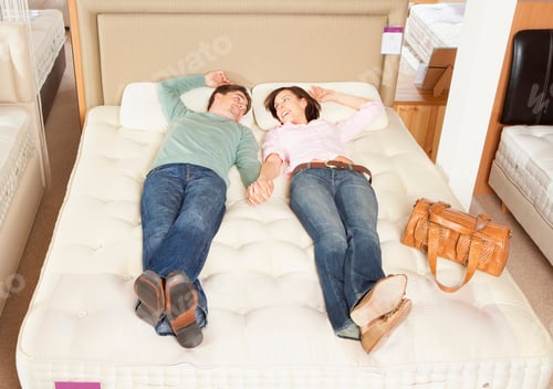 Preview: Couple lying on bed in furniture store