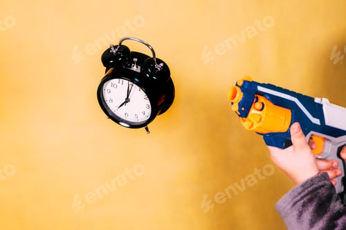 Preview: Boy shooting with a toy gun at an alarm clock.