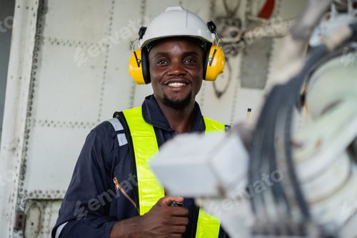 Preview: Engineer inspecting airplane engine with safety tools.