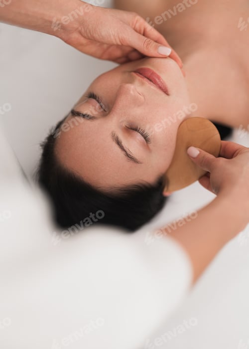 Preview: Crop professional cosmetician using gua sha tool during face massage