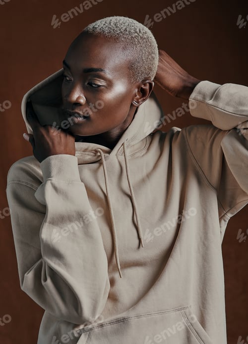 Preview: Studio shot of an attractive young woman wearing a hoodie and posing against a brown background