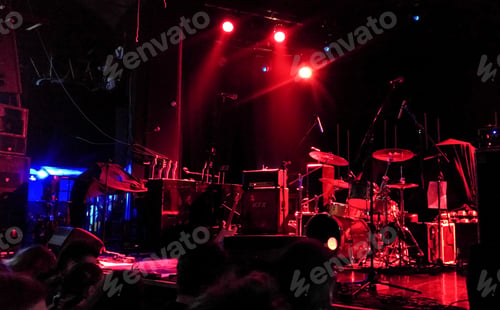 Preview: Res lights illuminating a concert stage with music instruments.