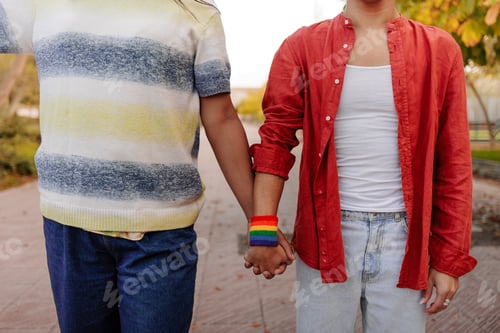 Preview: Latin transgender couple holding hands wearing rainbow bracelet: