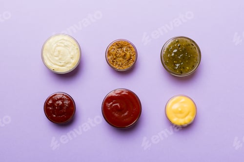 Preview: Different types of sauces in bowls on a colored Board . Top view. various sauces copy space