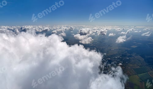 Preview: Aerial view from airplane window at high altitude of earth covered with white puffy cumulus clouds.