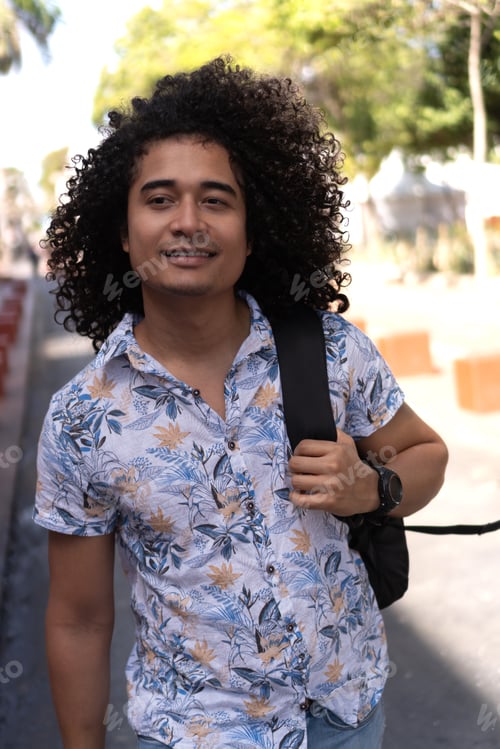 Preview: Man with afro hair, wearing a backpack, walking down the street