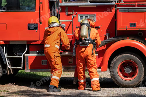 Preview: Firefighter wearing fire protection suite and oxygen tank exercise roll hose connect with fire truck