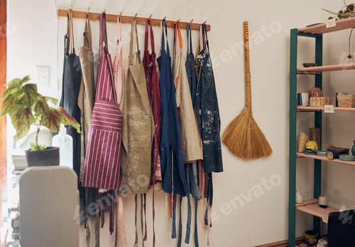 Preview: Clothes rack, apron and paint with a broom in an empty workshop or studio against still life wall f