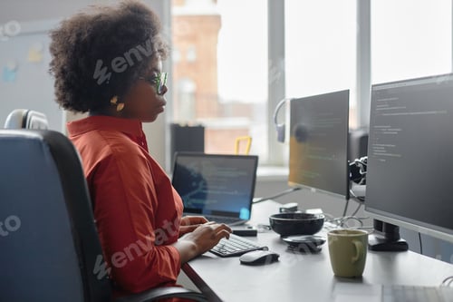 Preview: Curly IT Engineer Typing on Computer Reviewing Code