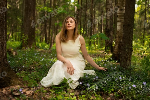 Preview: A young girl sits in a green forest. Woman in white dress