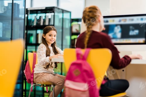Preview: adorable schoolgirls using desktop computers in library