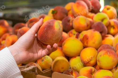 Preview: hand taking peach from grocery store shelf