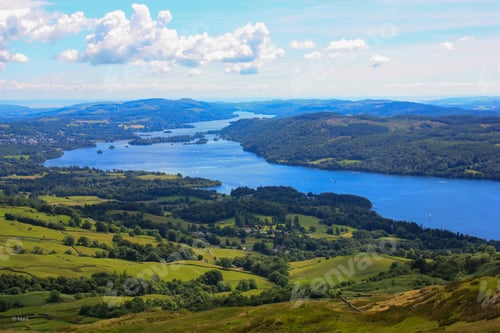Preview: Scenic view of a tranquil lake nestled in the embrace of lush green trees and majestic mountains.