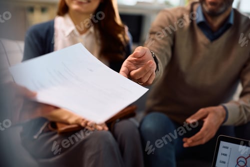 Preview: Close up of financial advisor offering contract to a couple during a meeting in the office.