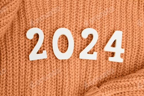 Visualização: Números de madeira 2024 e em um fundo tricotado de pêssego. Fundo festivo
.