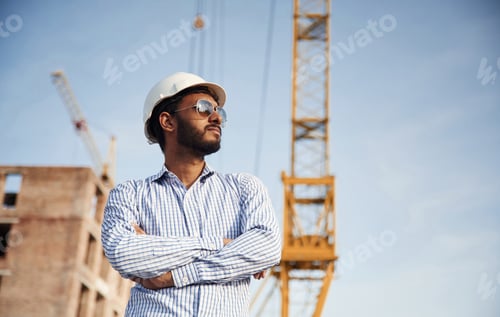 Preview: CEO is standing with arms crossed. Handsome Indian man is on the construction site