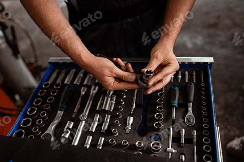 Preview: Skilled hands organizing a toolbox filled with various hand tools in a workshop setting