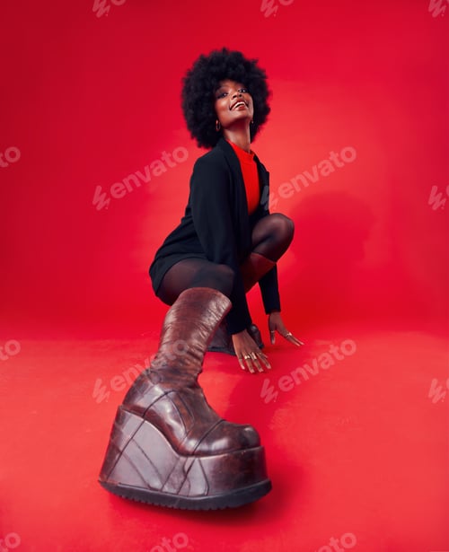 Preview: Fashion, boots and portrait of a black woman on a red background in studio to model trendy footwear