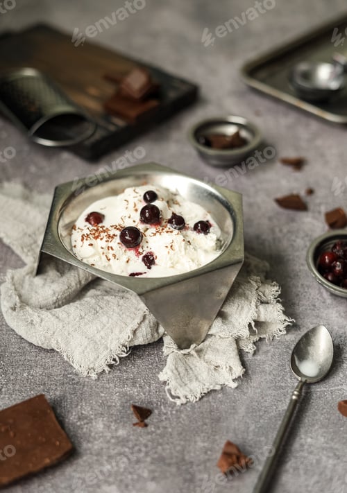 Preview: White vanilla ice cream with fresh berries and chocolate topping in a vintage vase on the table.