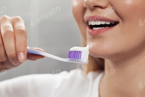 Preview: Woman holding brush with toothpaste in bathroom, closeup