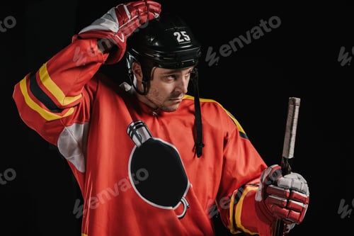Preview: professional hockey player adjusting helmet and holding hockey stick isolated on black