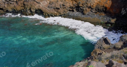 Preview: View of ocean waves break on rocks of Tenerife island cliffs in a blue ocean. Green nature and