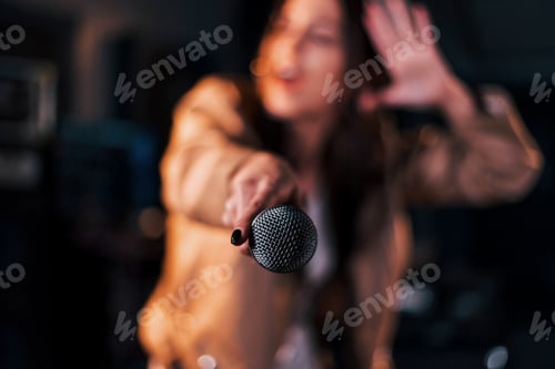 Preview: Close up view of microphone. Young beautiful female performer rehearsing in a recording studio