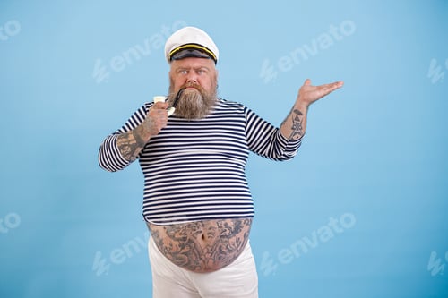 Preview: Dashing fat man with tattoos in sailor suit points aside on light blue background