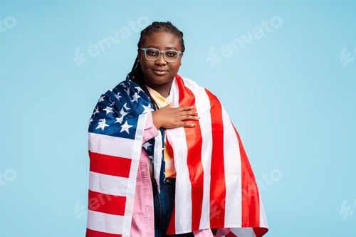 Preview: Portrait serious beautiful African American woman, patriot wearing eyeglasses, holding American flag
