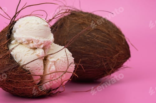 Preview: Vanilla ice cream balls in an empty coconut decorated with mint leaves on a pink background