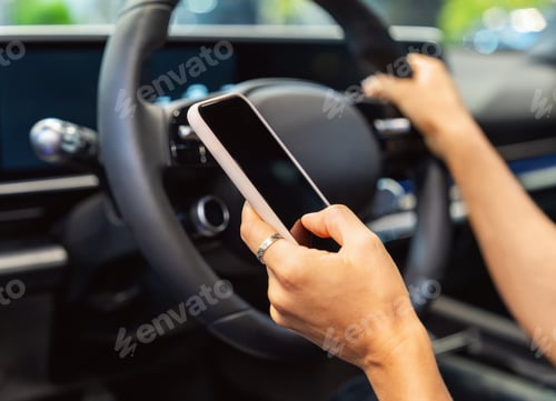 Preview: Close-up of smartphone in hand of woman behind steering wheel